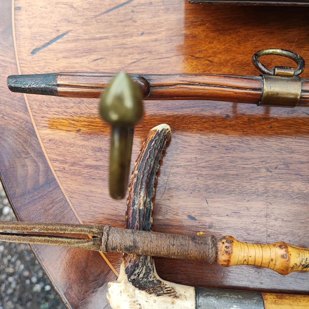 A carved wooden fox head whip rack mounted inside a brass stirrup frame with horizontal brass hooks on a wooden shaft. View IV