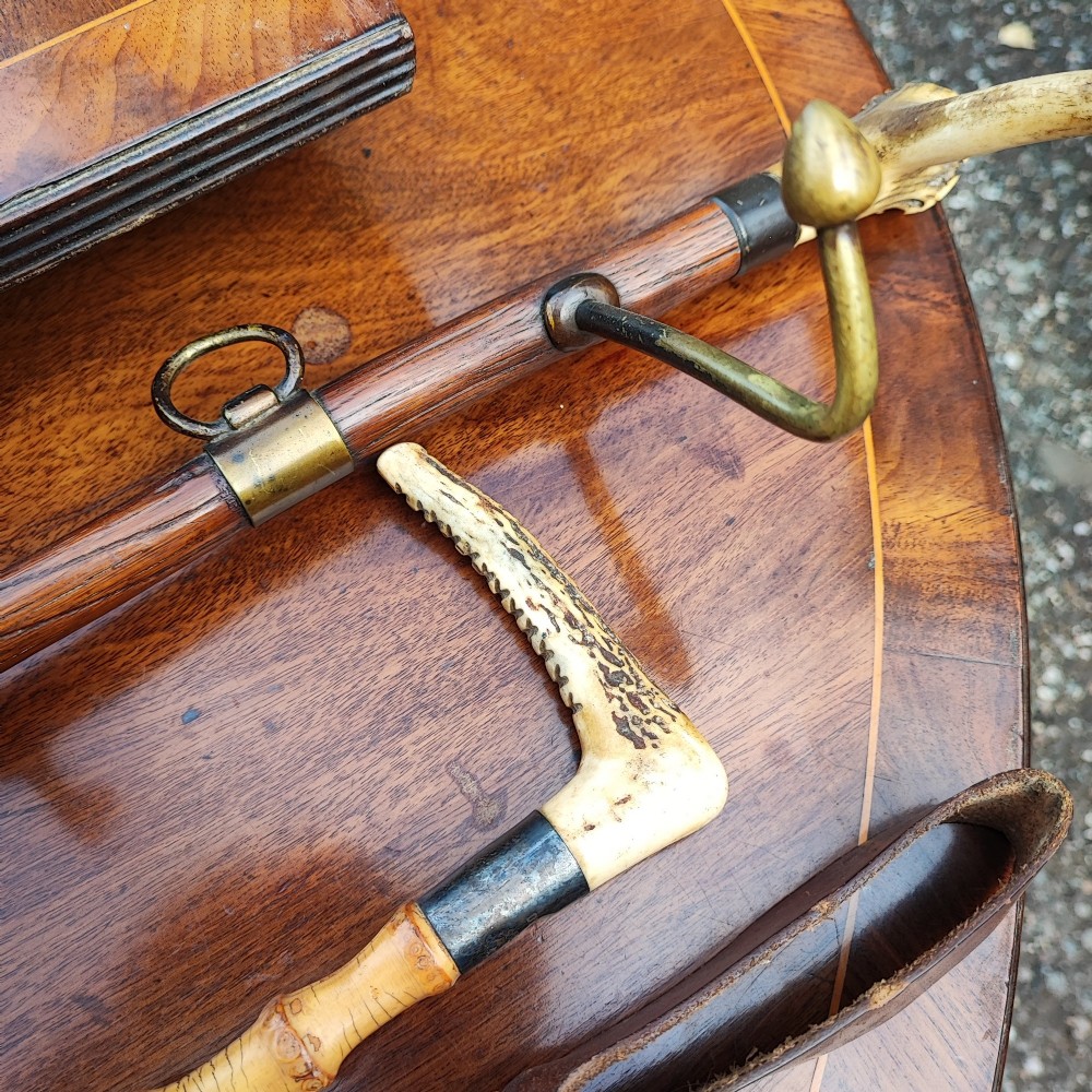 A carved wooden fox head whip rack mounted inside a brass stirrup frame with horizontal brass hooks on a wooden shaft. View VI