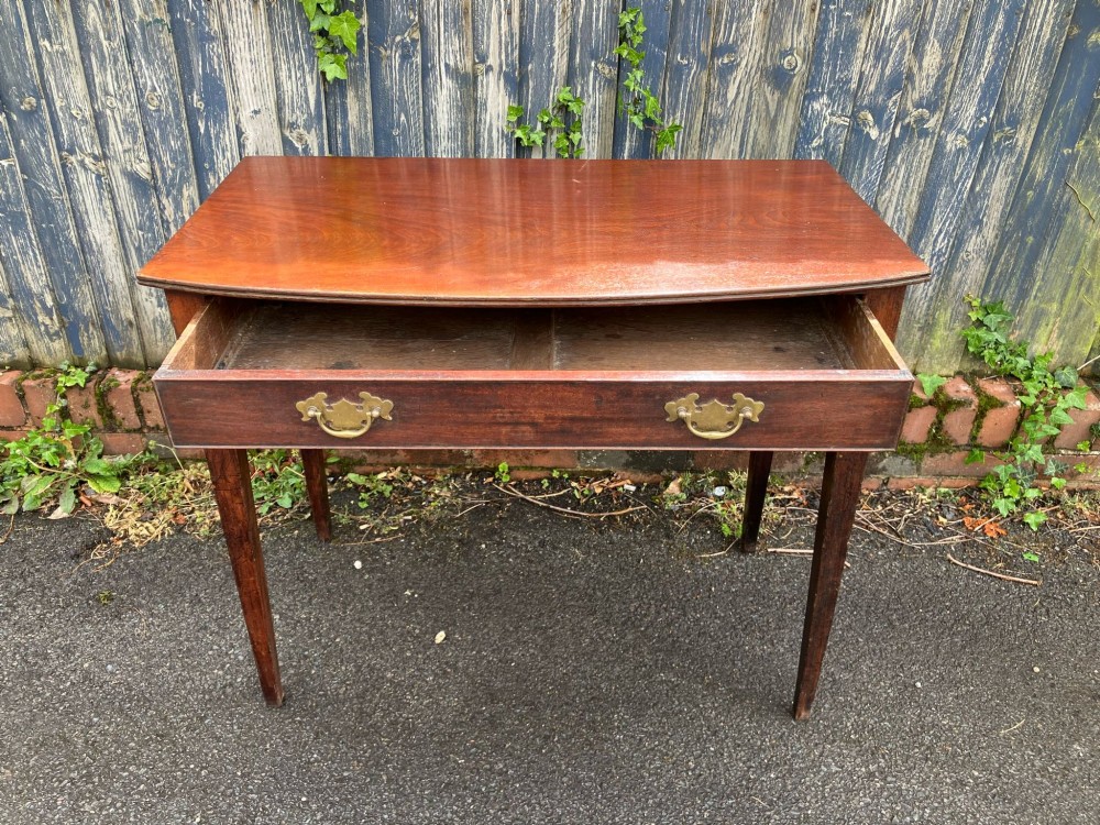 A Georgian bow-fronted mahogany side table featuring a single drawer with two brass handles and supported on four square tapered legs. View II