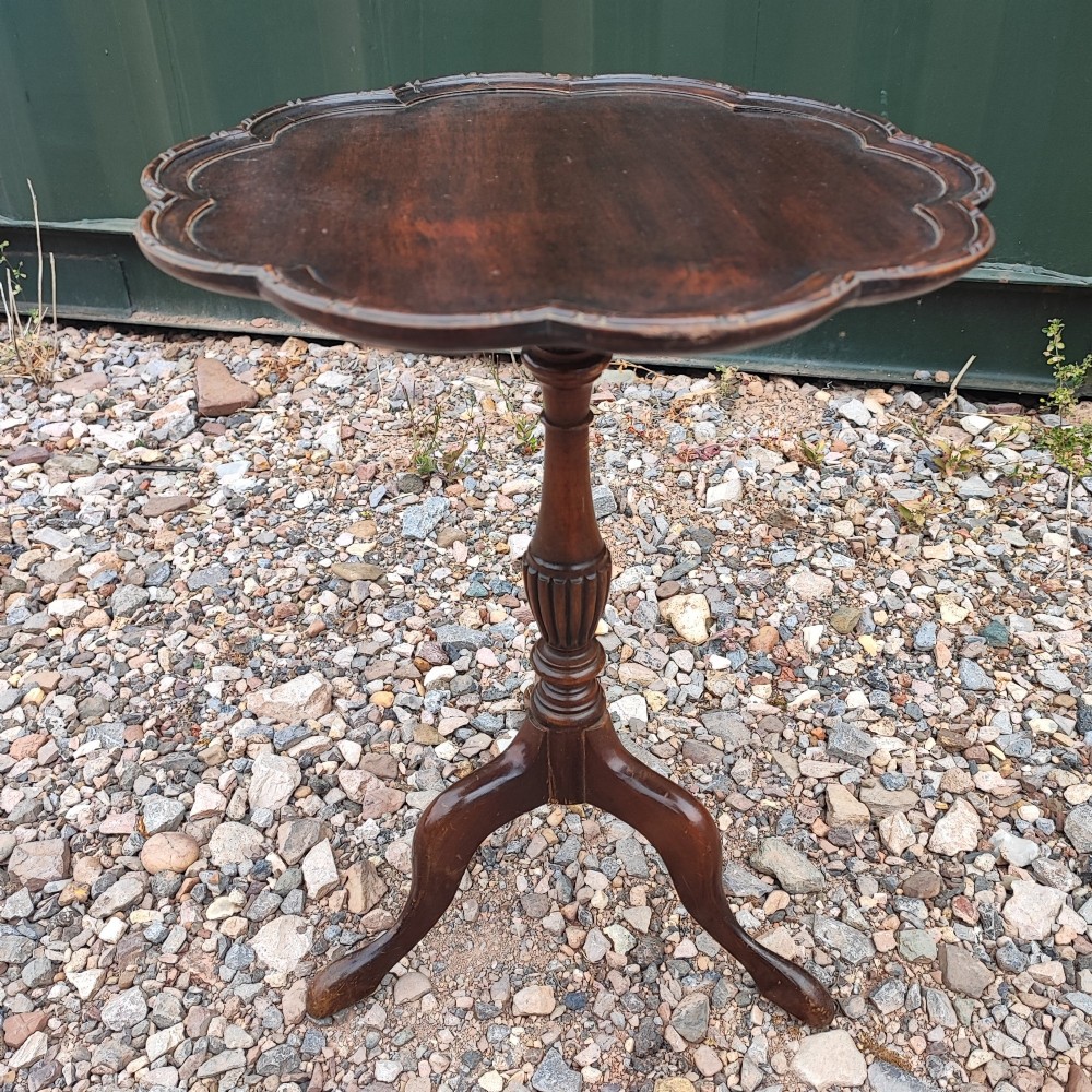 A dark mahogany tripod wine table featuring a scalloped rim top, turned central column, and three cabriole legs.