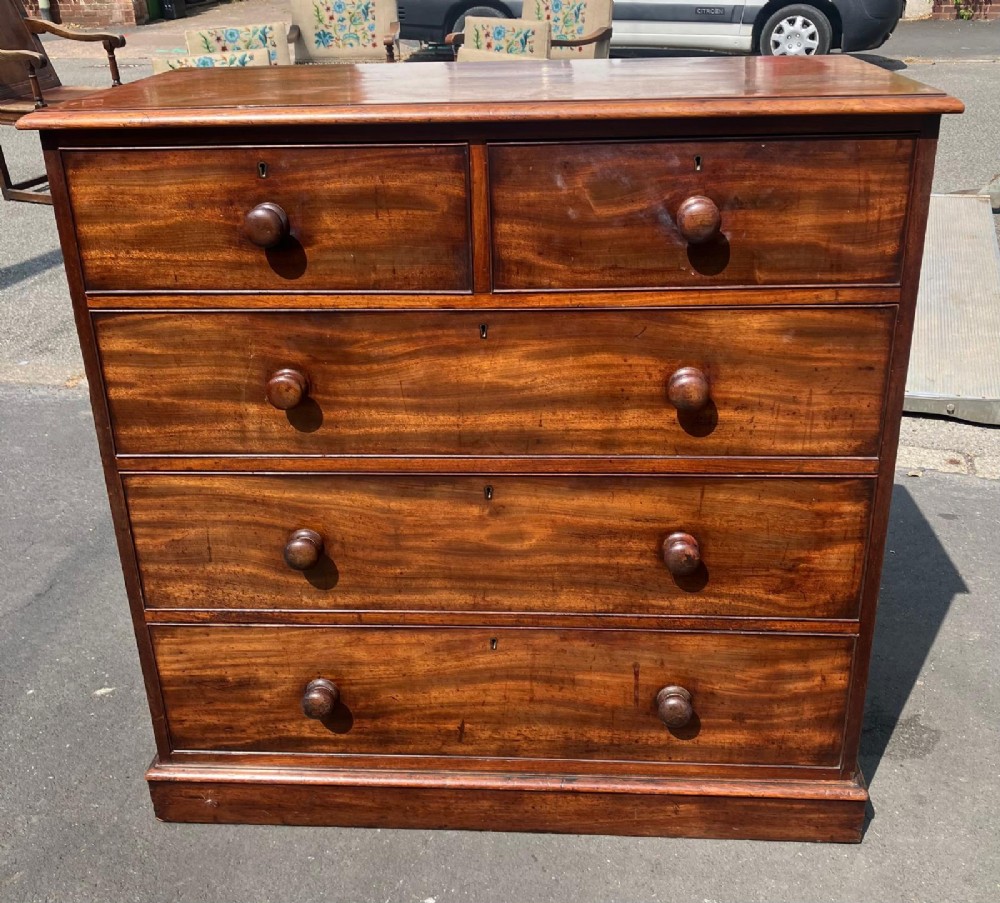 A Victorian flame mahogany chest of drawers featuring a two-over-three drawer configuration, turned wooden knobs, and a solid plinth base.