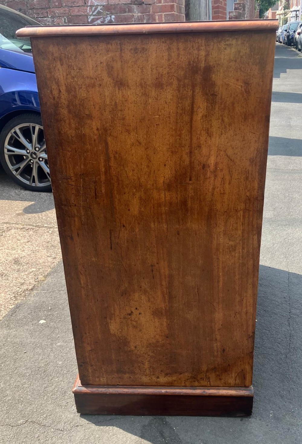 A Victorian flame mahogany chest of drawers featuring a two-over-three drawer configuration, turned wooden knobs, and a solid plinth base. View V