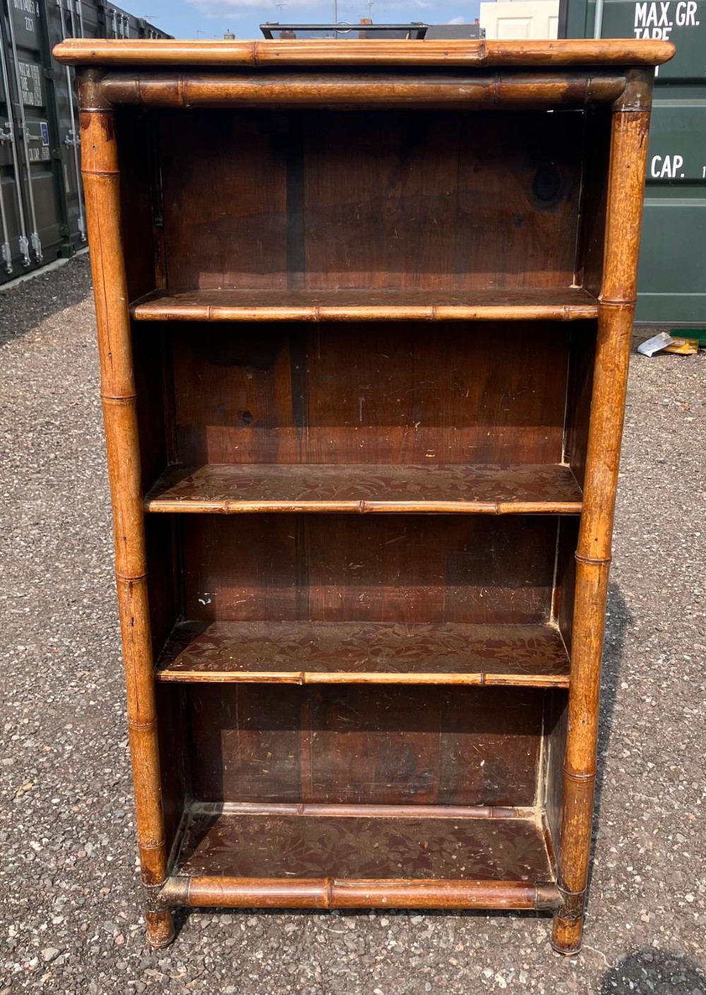 A Victorian open bookcase constructed from warm brown bamboo poles with four patterned lacquered shelves.
