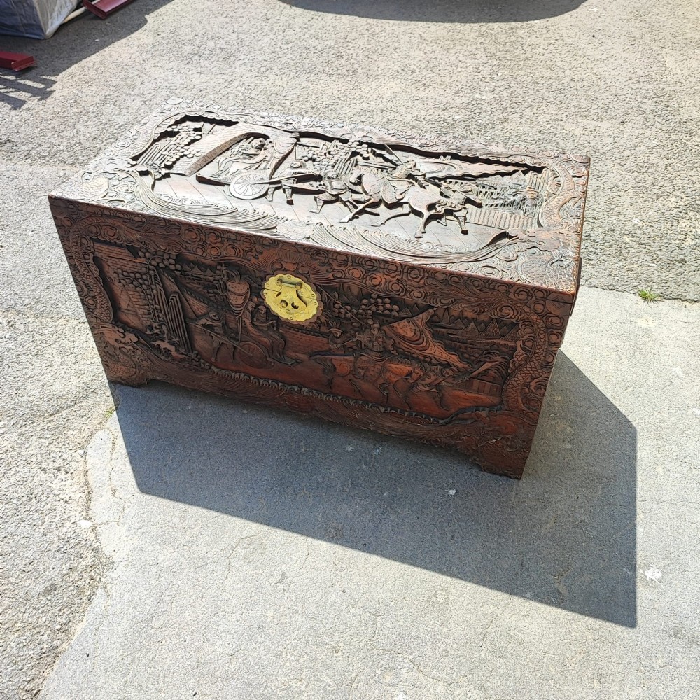 A relief-carved camphor wood trunk with relief panel depictions of figures on horseback and a central brass clasp. View VII