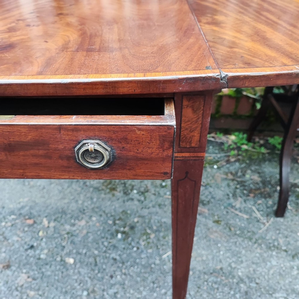 A Georgian mahogany Pembroke table featuring two hinged drop leaves, a central frieze drawer with brass ring handles, boxwood stringing, and tapered legs on brass castors. View VII