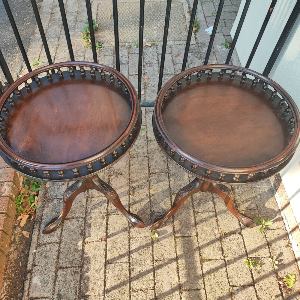 A pair of dark mahogany tripod tables featuring circular tops with spindle galleries, turned shafts, and carved cabriole legs with claw and ball feet. View II