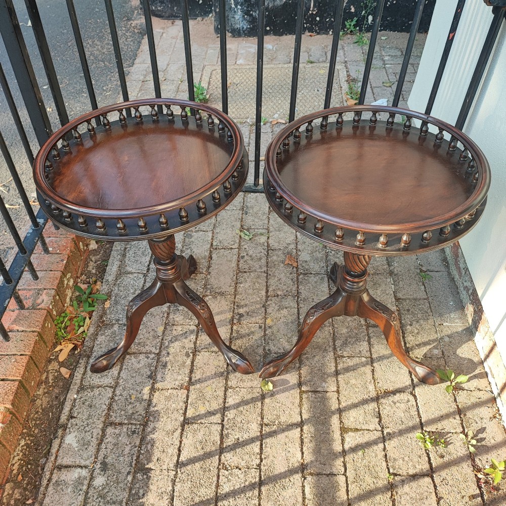 A pair of dark mahogany tripod tables featuring circular tops with spindle galleries, turned shafts, and carved cabriole legs with claw and ball feet. View VII