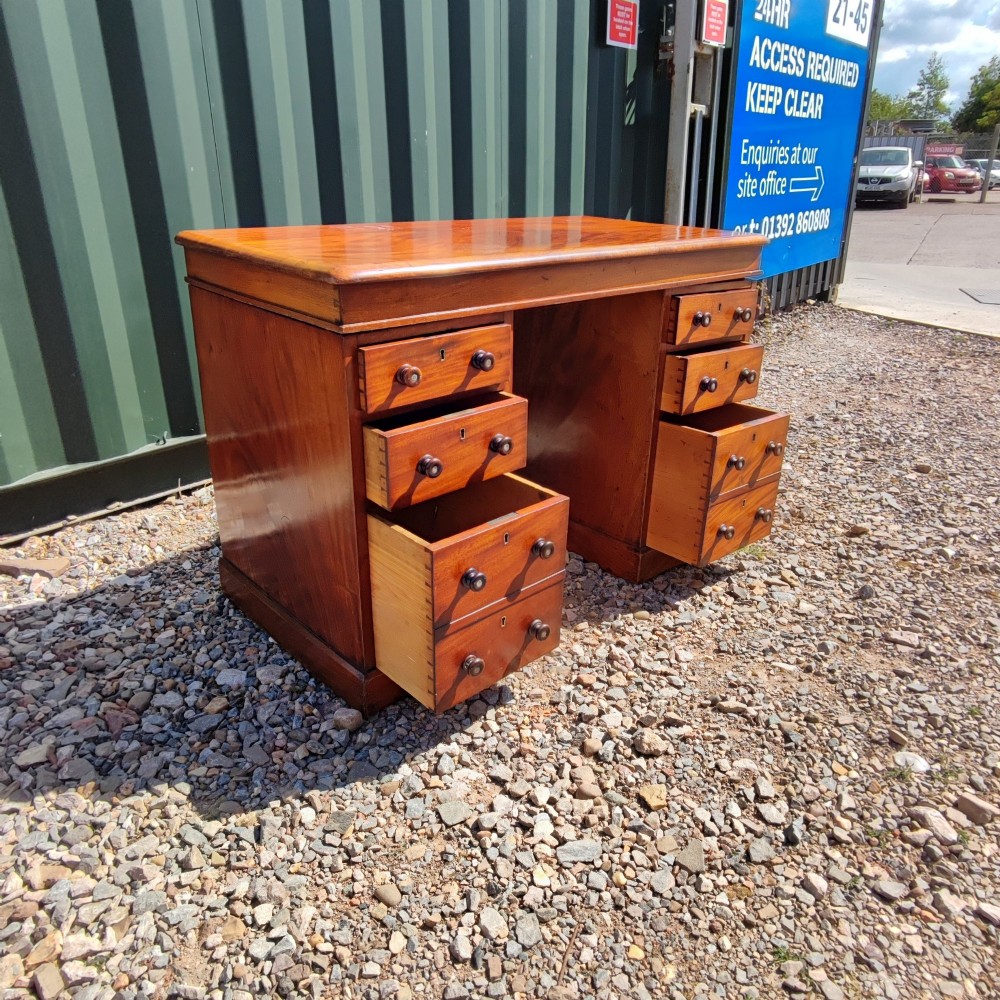 An antique mahogany pedestal desk featuring eight drawers with turned wooden knobs and a polished rectangular top surface. View IV