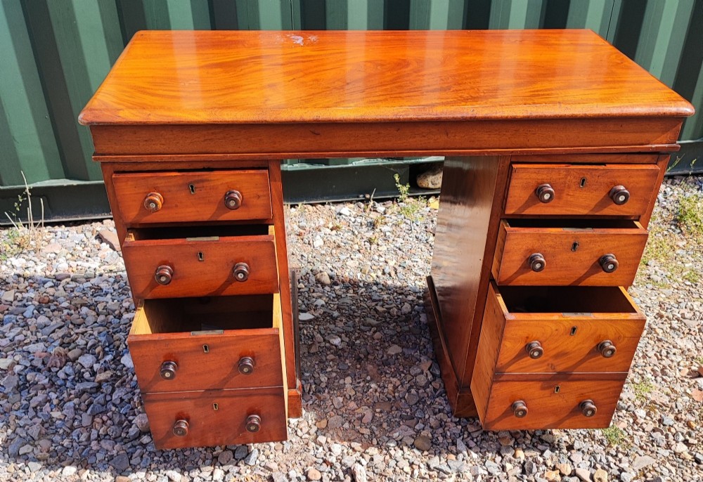 An antique mahogany pedestal desk featuring eight drawers with turned wooden knobs and a polished rectangular top surface. View VI