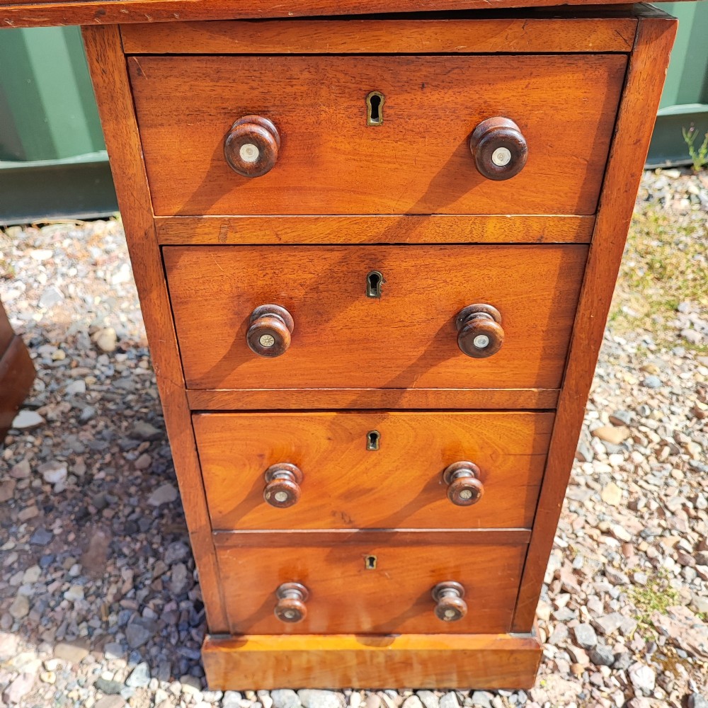 An antique mahogany pedestal desk featuring eight drawers with turned wooden knobs and a polished rectangular top surface. View VII