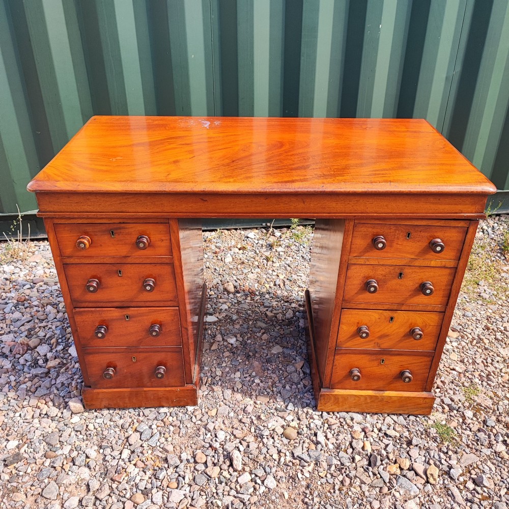 An antique mahogany pedestal desk featuring eight drawers with turned wooden knobs and a polished rectangular top surface. View IX