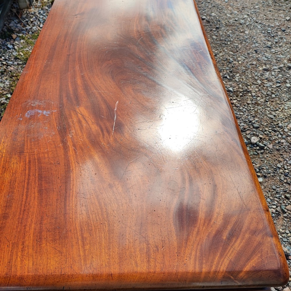 An antique mahogany pedestal desk featuring eight drawers with turned wooden knobs and a polished rectangular top surface. View X