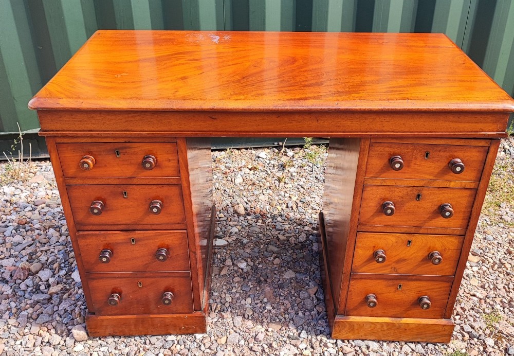 An antique mahogany pedestal desk featuring eight drawers with turned wooden knobs and a polished rectangular top surface. View XI