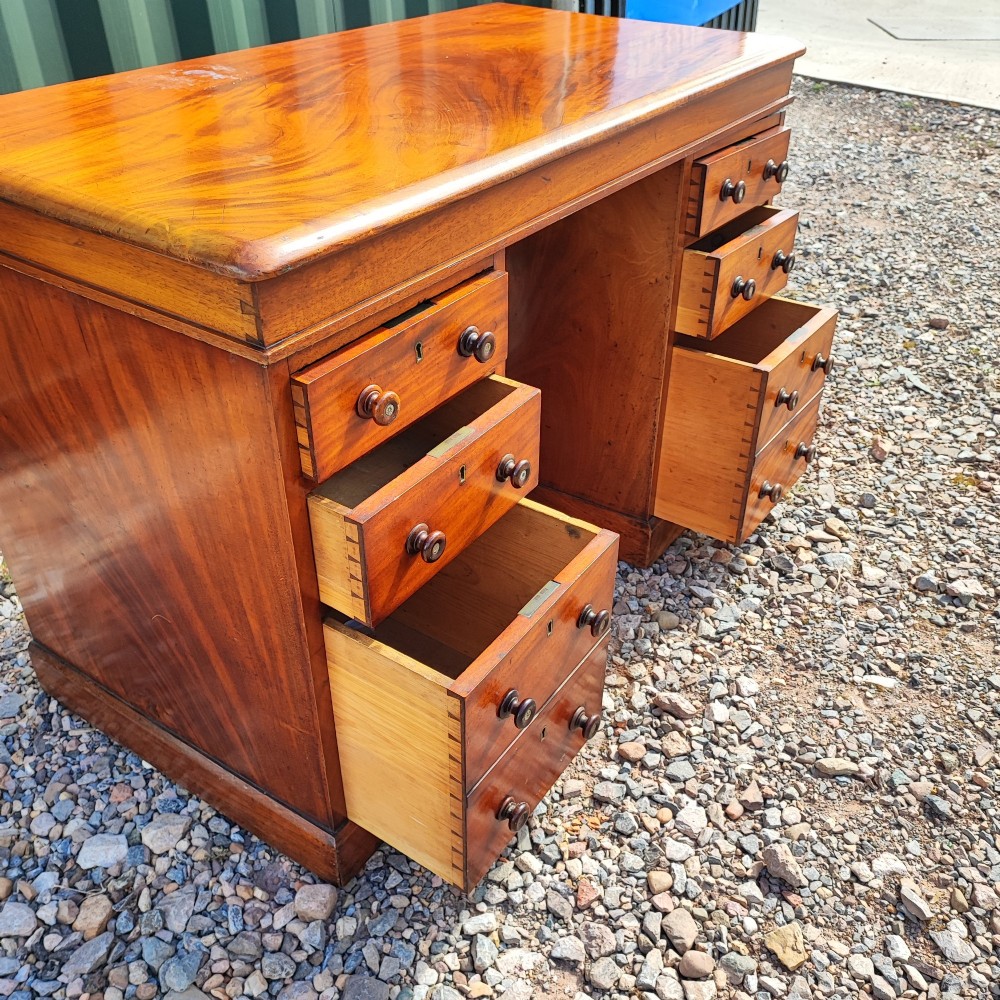 An antique mahogany pedestal desk featuring eight drawers with turned wooden knobs and a polished rectangular top surface. View XIII