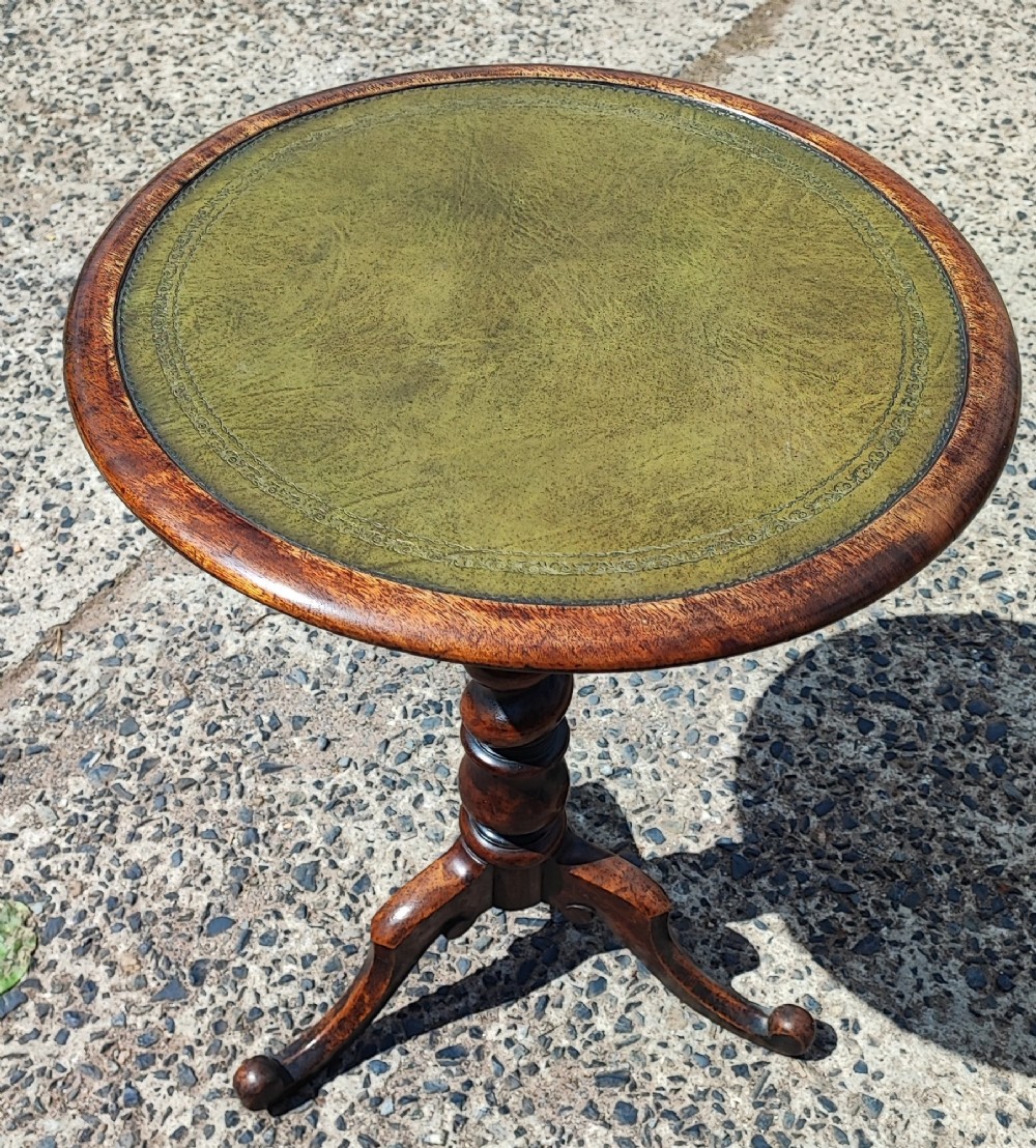 A small circular mahogany wine table with a green leather inset top supported by a turned pedestal column on three cabriole legs. View II
