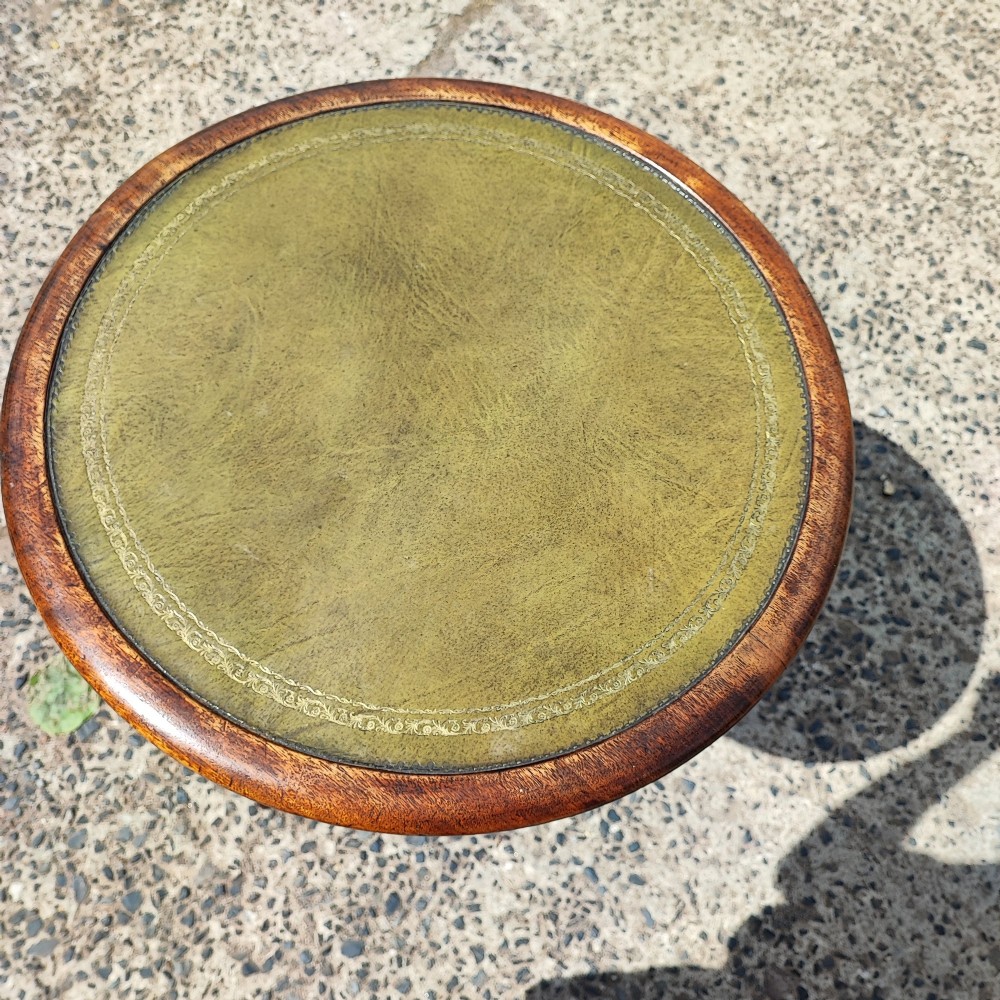 A small circular mahogany wine table with a green leather inset top supported by a turned pedestal column on three cabriole legs. View VI