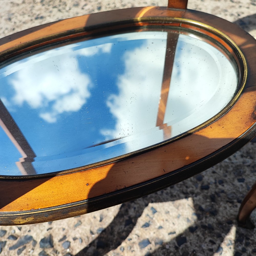 An antique oval satinwood etagere featuring three tiers with glass panels, brass trim, and curved legs adorned with bronze mounts. View X