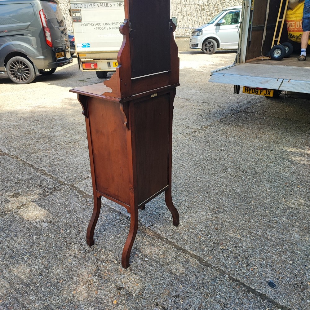 A narrow Victorian mahogany standing dressing table featuring an integrated swivel mirror above a single drawer, storage cupboard, and curved legs. View V