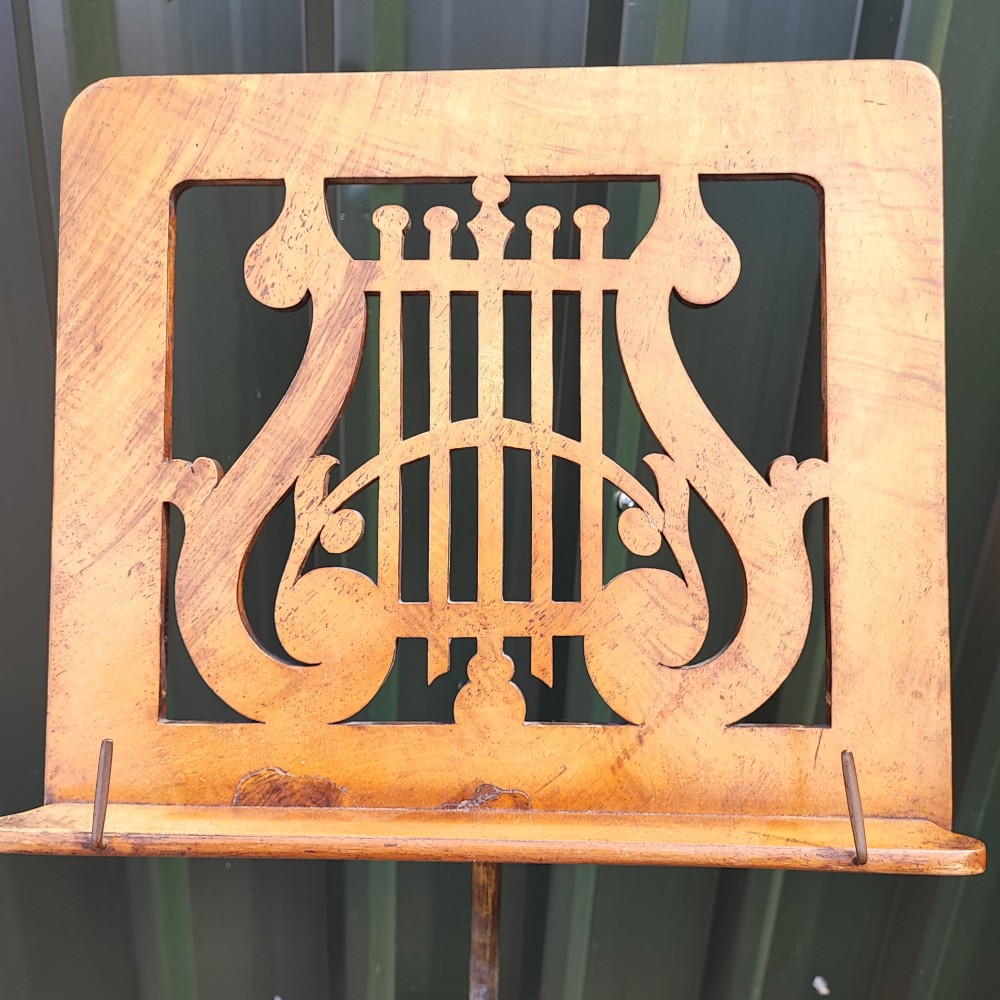 A Victorian walnut music stand featuring a fretwork lyre rest, height-adjustable brass stem, turned column, and carved tripod legs. View II