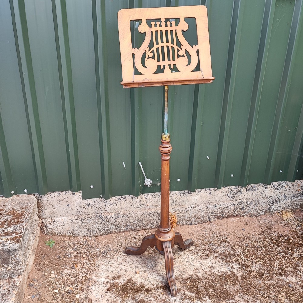 A Victorian walnut music stand featuring a fretwork lyre rest, height-adjustable brass stem, turned column, and carved tripod legs. View VIII