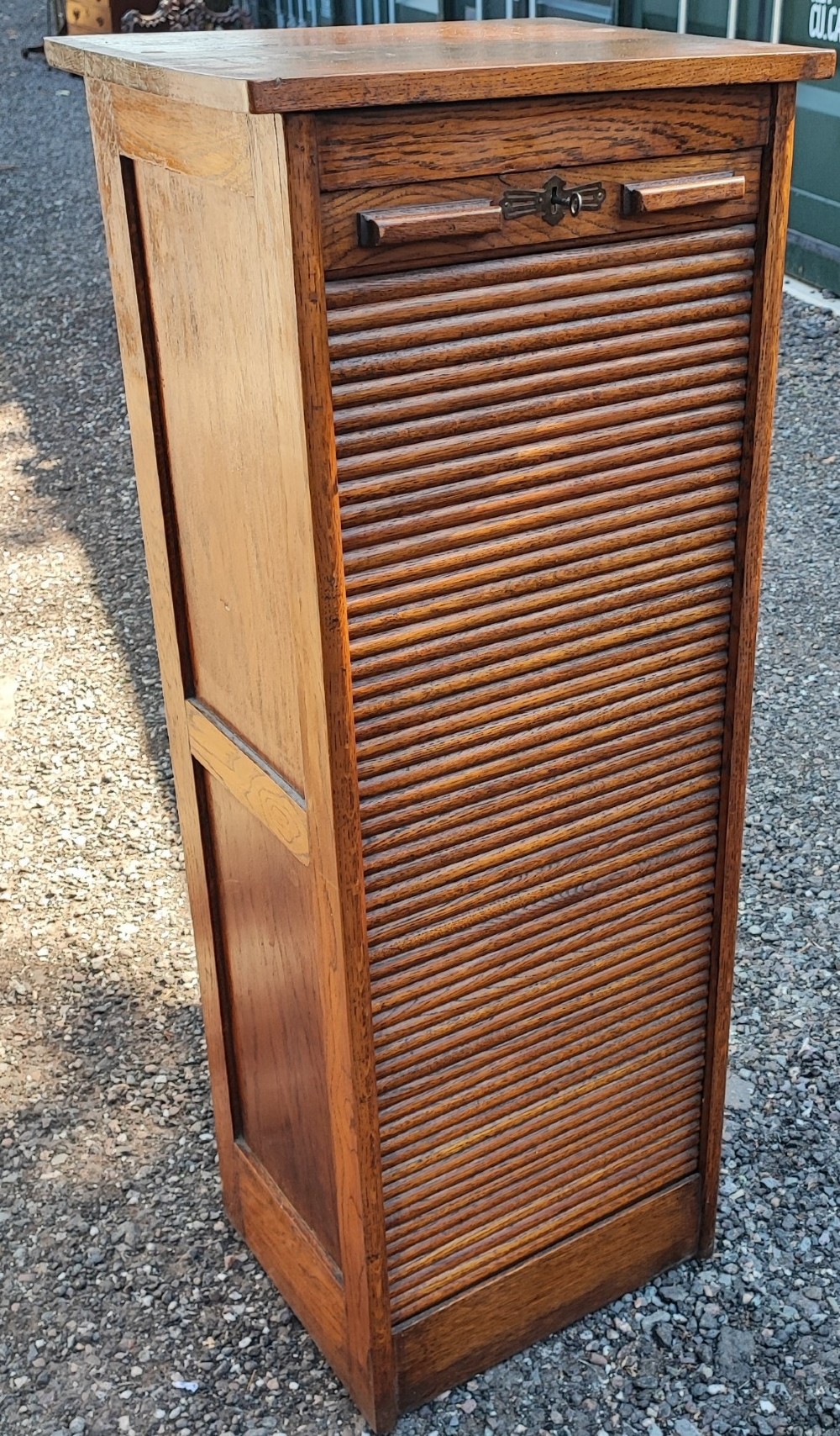 A tall Edwardian oak filing cabinet featuring a slatted wooden tambour front shutter, keyhole escutcheon with key, and wooden pull handles. View VIII