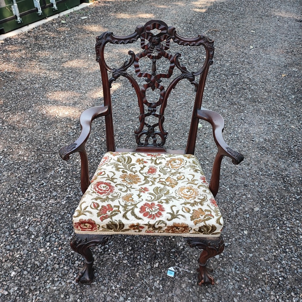 An antique carved mahogany Chippendale style armchair featuring an intricate ribbon-back splat, carved armrests, floral pattern fabric seat, and cabriole legs with ball-and-claw feet. View VI