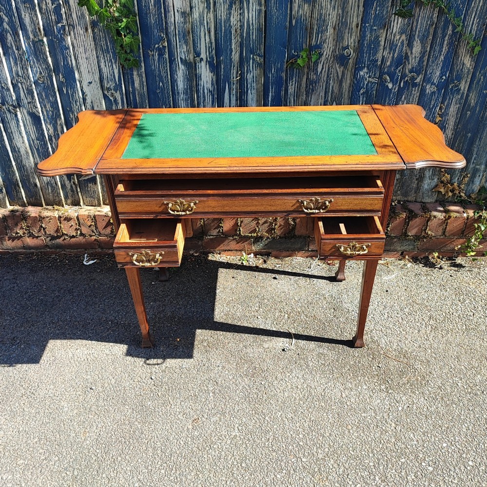 A mahogany drop-leaf writing desk with a green inset writing surface, three drawer handles, and extended side flaps. View III