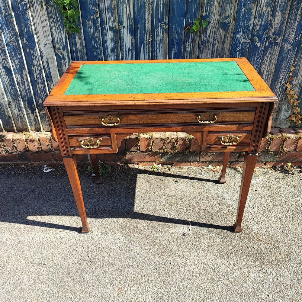 A mahogany drop-leaf writing desk with a green inset writing surface, three drawer handles, and extended side flaps. View IV