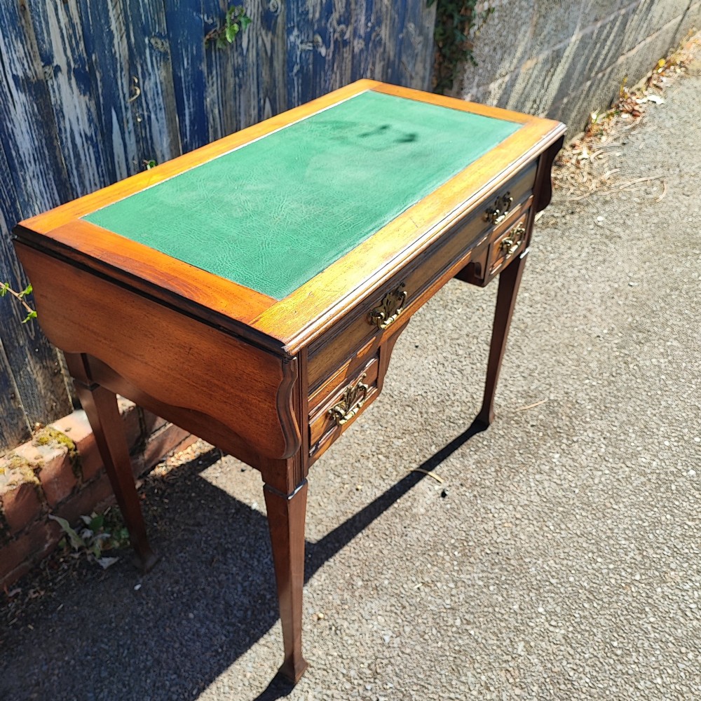 A mahogany drop-leaf writing desk with a green inset writing surface, three drawer handles, and extended side flaps. View V