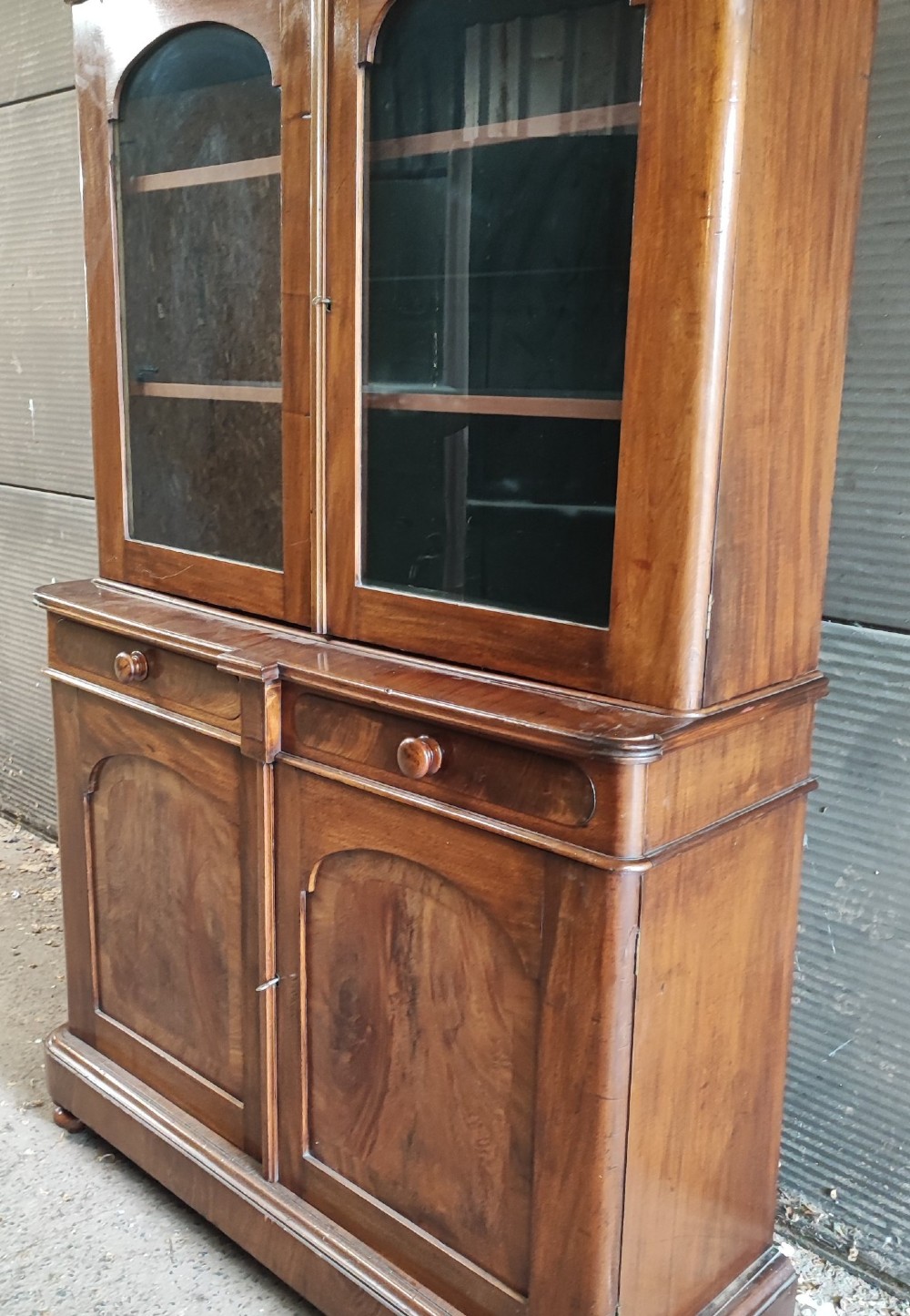A tall Victorian mahogany bookcase featuring two glazed upper doors, two frieze drawers, and a double-door lower cupboard. View II