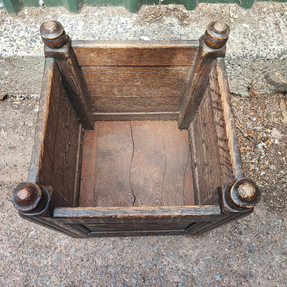A square dark oak open box featuring carved diamond motifs on the front panel and turned finials atop four corner posts. View V