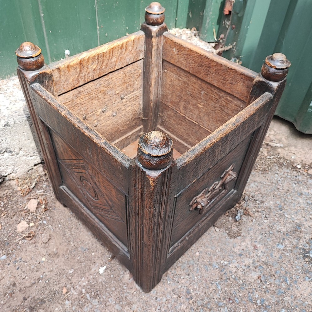 A square dark oak open box featuring carved diamond motifs on the front panel and turned finials atop four corner posts. View VI