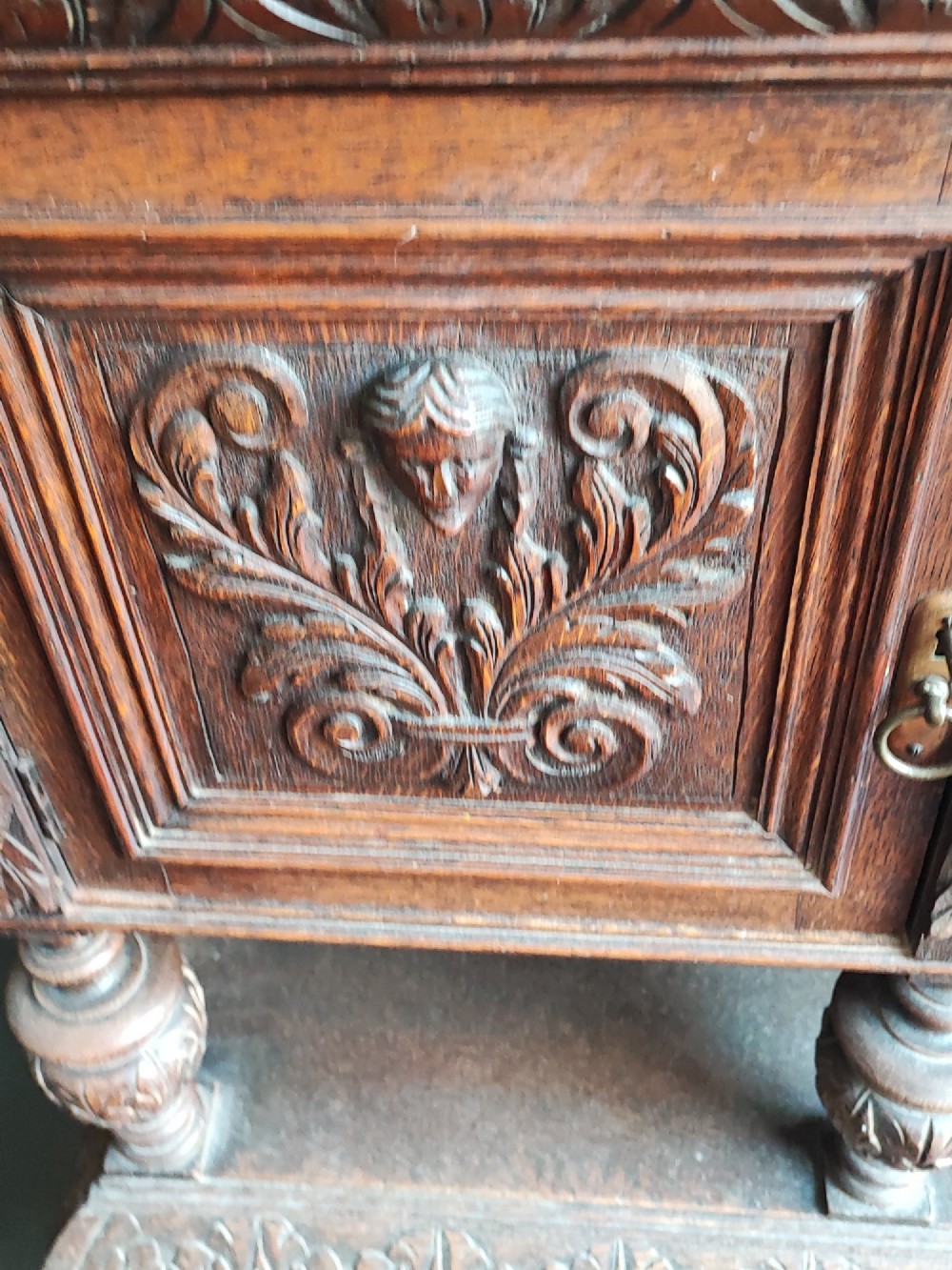 A heavily carved dark oak sideboard featuring a mirrored top section flanked by glazed cabinet doors, resting on turned bulbous supports and a lower shelf. View II