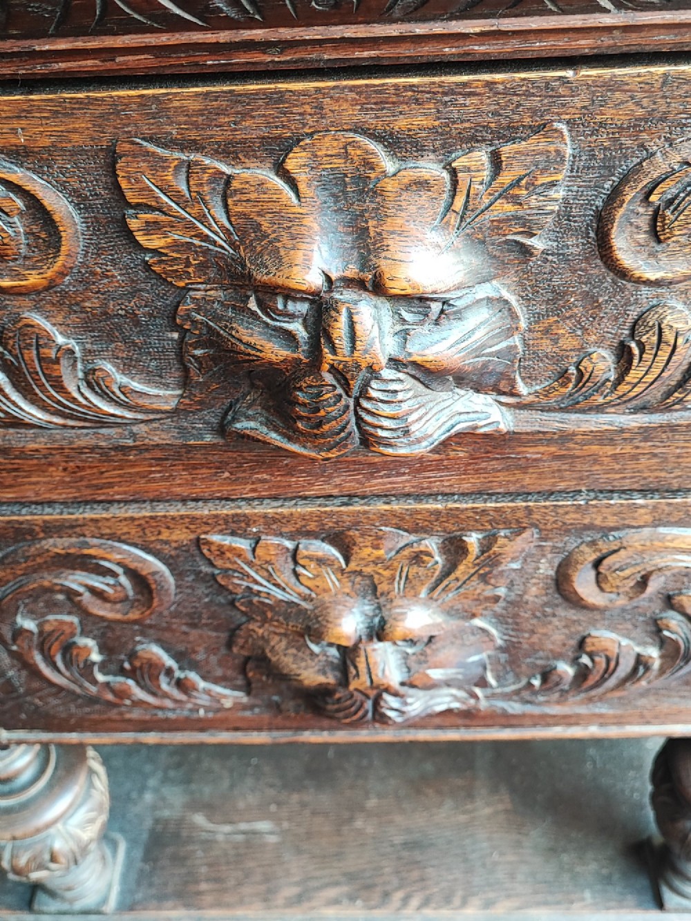 A heavily carved dark oak sideboard featuring a mirrored top section flanked by glazed cabinet doors, resting on turned bulbous supports and a lower shelf. View III