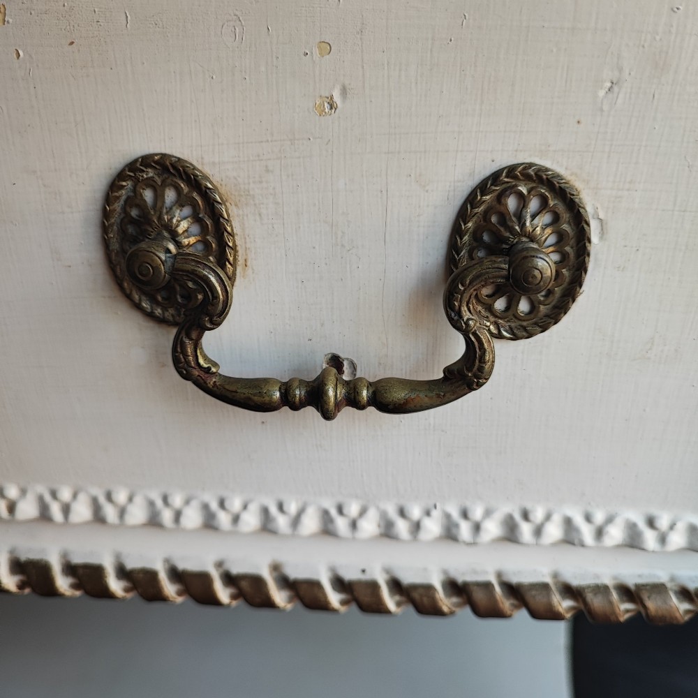 An off-white painted antique dressing table featuring a central triptych mirror, carved gilt details, three drawers with brass handles, and fluted legs on castors. View VI