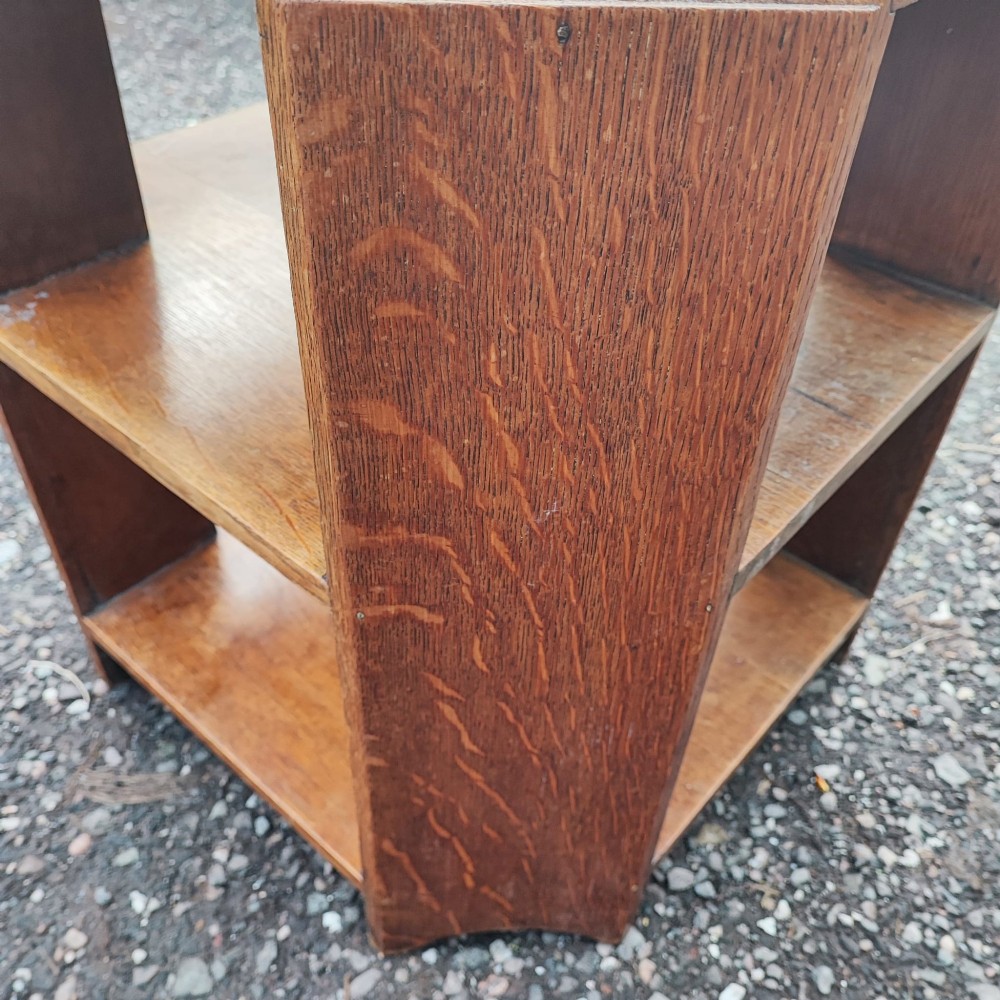 An octagonal antique oak side table featuring open lower shelves for books, showcasing quarter-sawn wood grain. View II