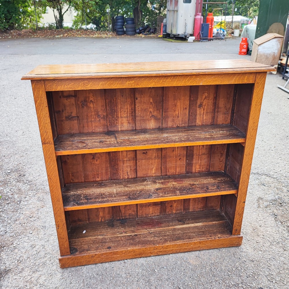 A low Victorian open oak bookcase featuring three fixed shelves, a planked timber back, and a moulded top edge. View II