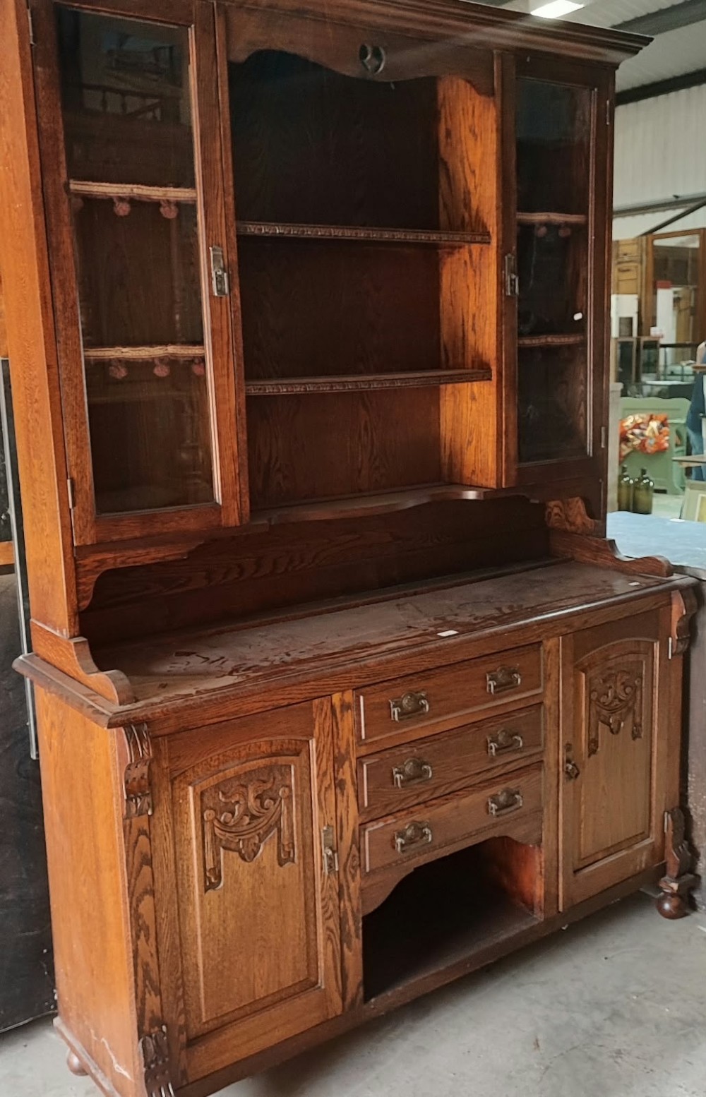 A Victorian tiger oak Welsh dresser featuring a glazed upper display rack above a base unit with carved panel doors and central drawers.