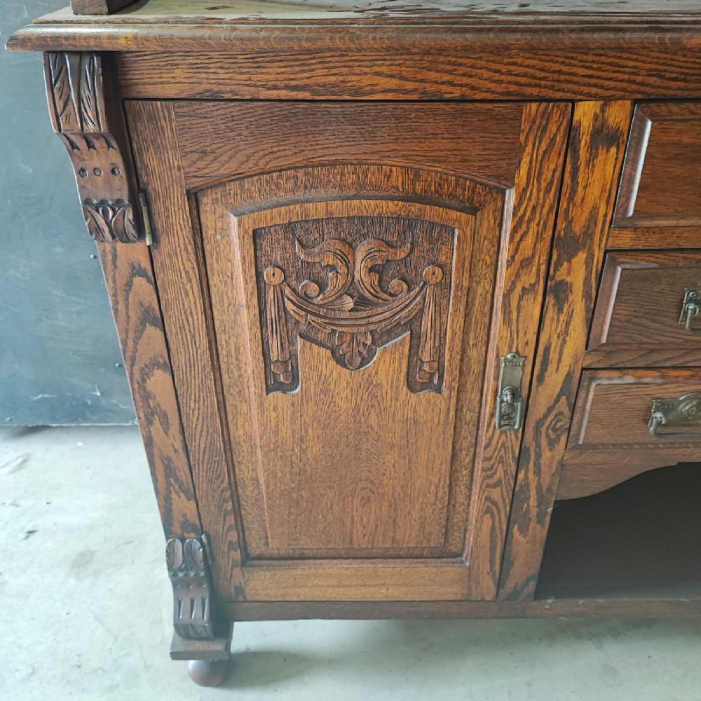 A Victorian tiger oak Welsh dresser featuring a glazed upper display rack above a base unit with carved panel doors and central drawers. View III