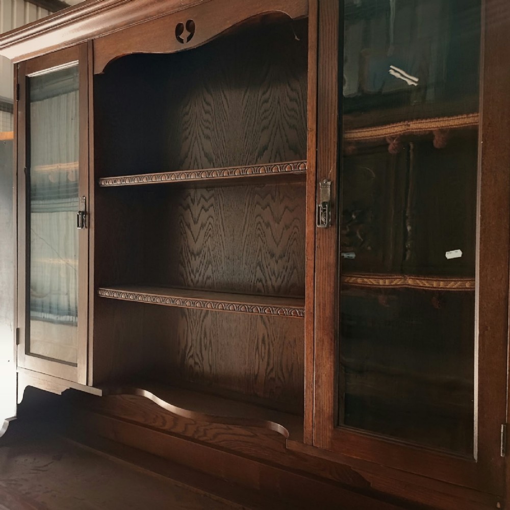 A Victorian tiger oak Welsh dresser featuring a glazed upper display rack above a base unit with carved panel doors and central drawers. View IV