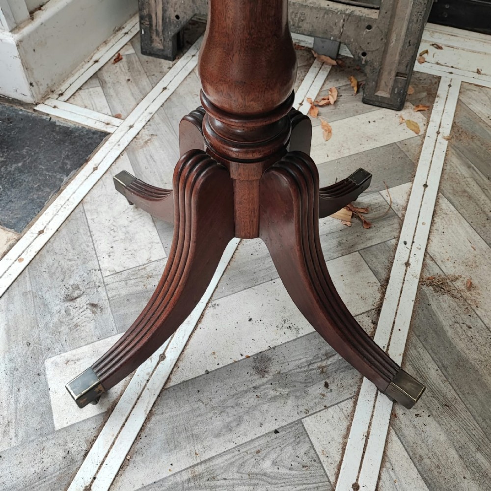 A Regency period mahogany tea table featuring a fold-over polished top, a central pedestal base, and four reeded sabre legs with brass feet. View V