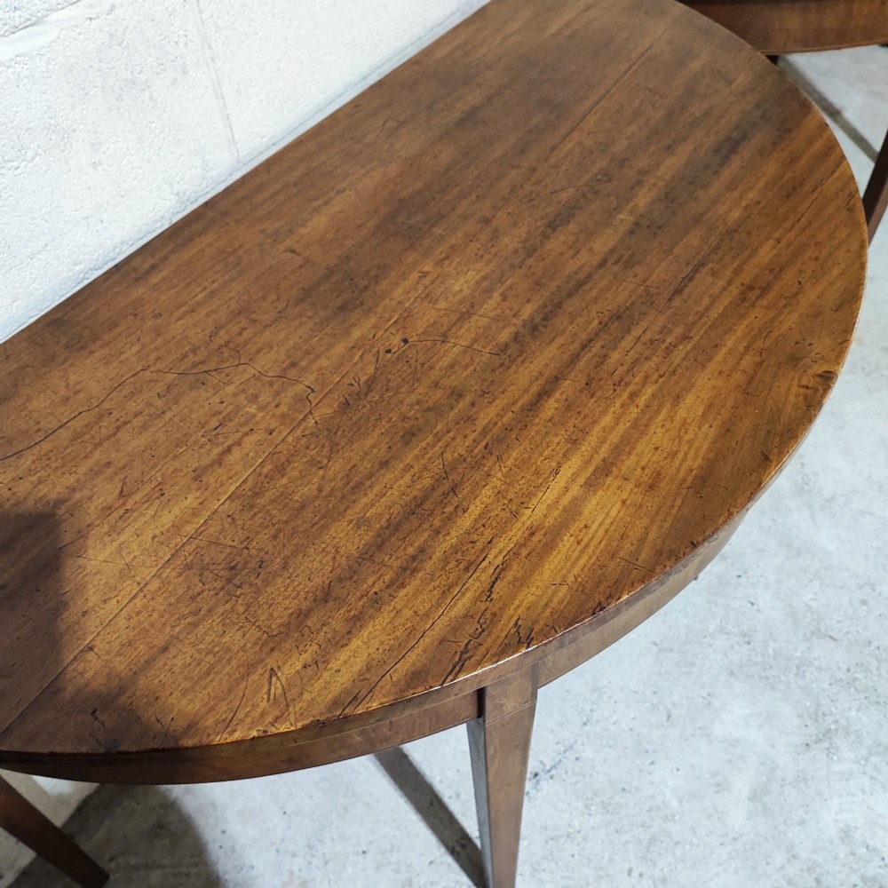 A pair of antique Georgian mahogany demi-lune console tables featuring semi-circular tops and straight tapered legs. View III