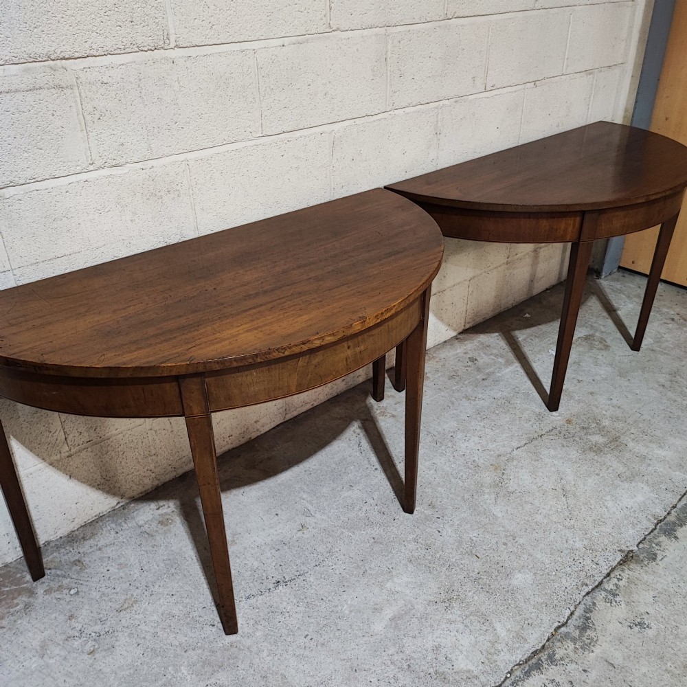 A pair of antique Georgian mahogany demi-lune console tables featuring semi-circular tops and straight tapered legs. View V