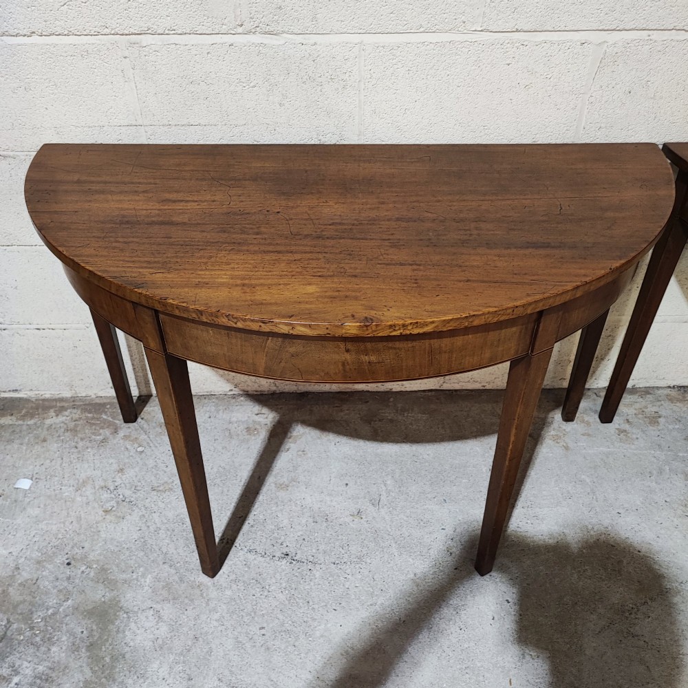 A pair of antique Georgian mahogany demi-lune console tables featuring semi-circular tops and straight tapered legs. View VII