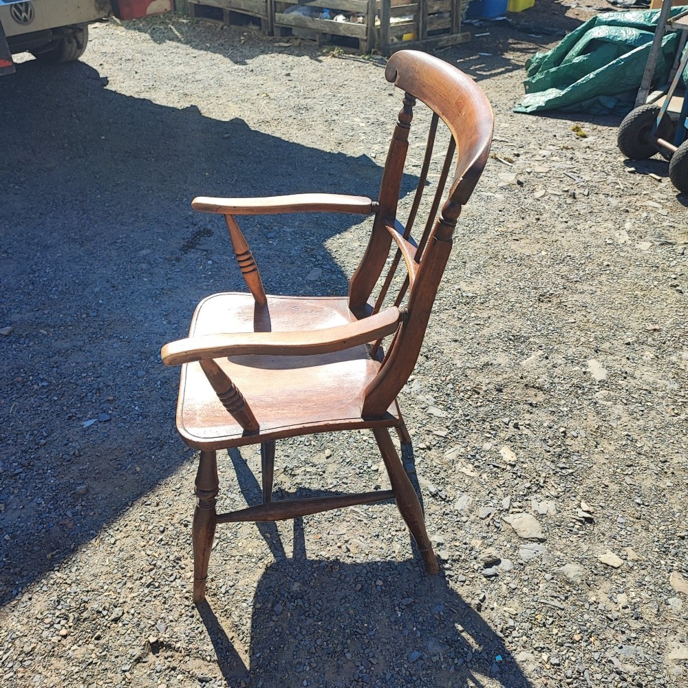 An antique wooden country armchair featuring turned front legs, a spindle backrest with a carved top rail, and curved armrests. View III