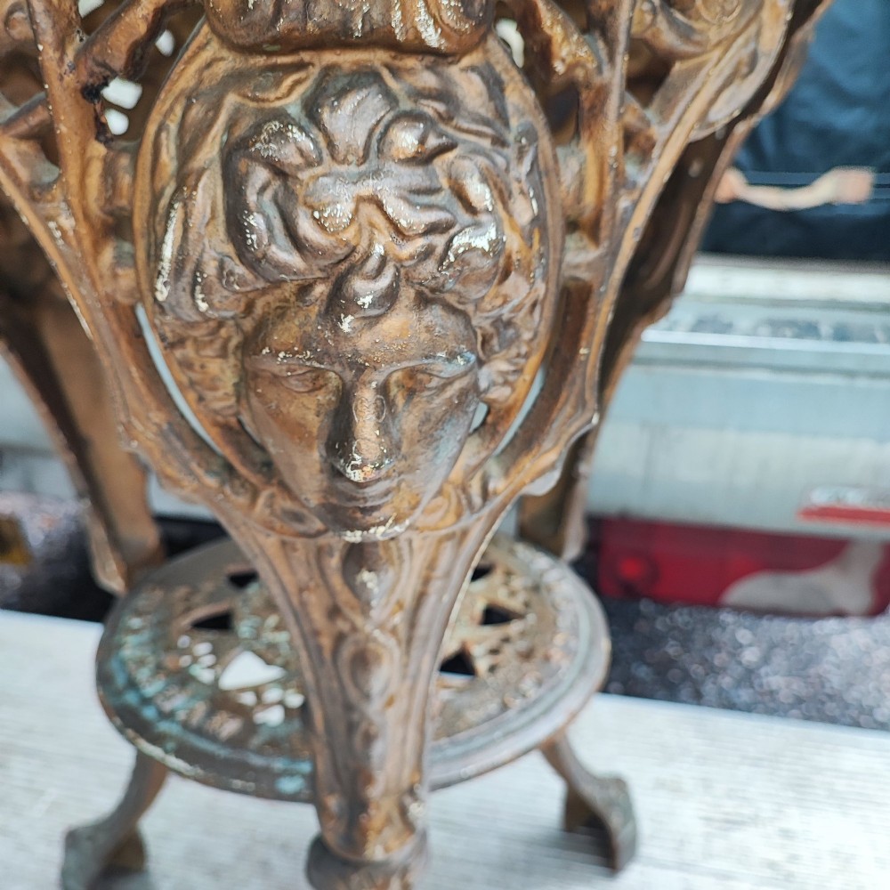 A Victorian cast iron tripod pub table featuring ornate leg castings with classical face motifs, a pierced lower circular tier, and a round wooden tabletop. View II