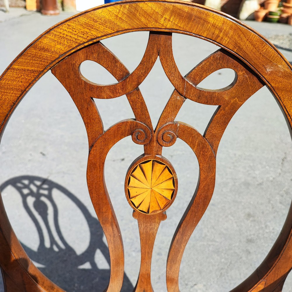 A pair of mahogany armchairs featuring oval backs with pierced splats, inlaid oval paterae, curved armrests, and floral embroidered upholstered seats. View III