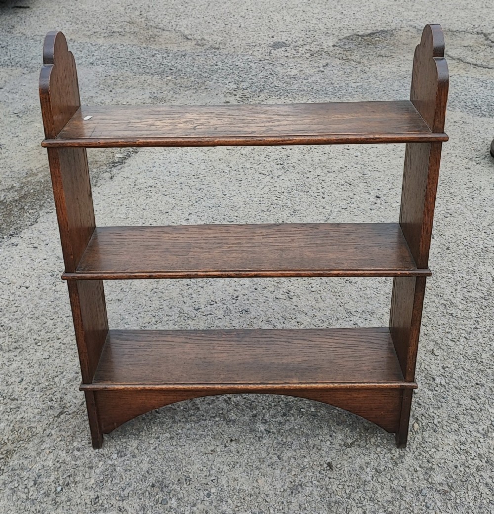 A low three-tier open oak bookcase featuring shaped side uprights and an arched apron base. View IV