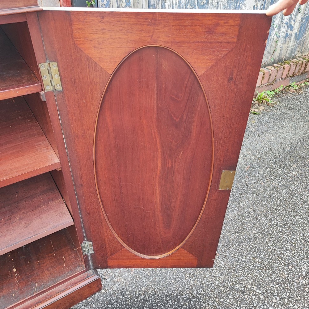 An antique dark mahogany two-door storage cupboard with decorative oval inlay panels set on a solid plinth base. View III