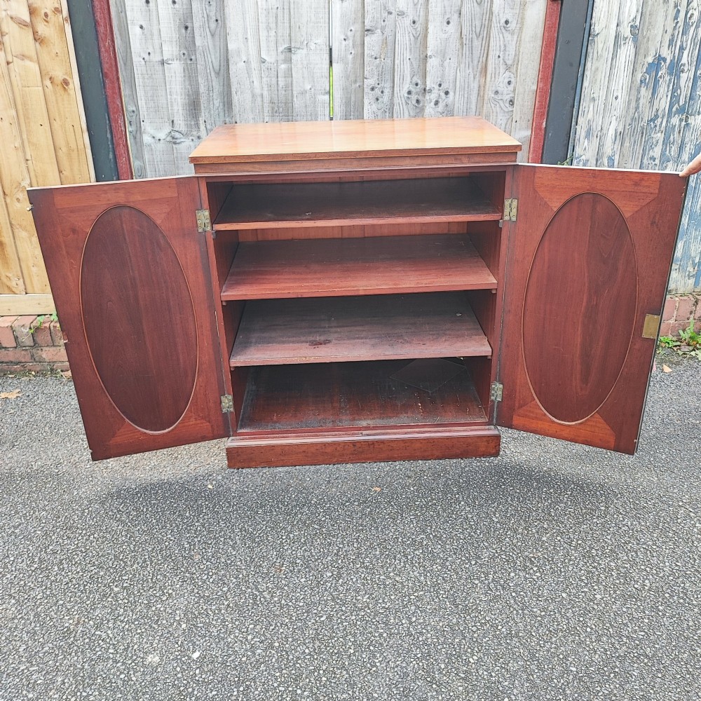 An antique dark mahogany two-door storage cupboard with decorative oval inlay panels set on a solid plinth base. View VI